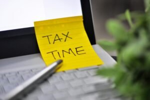 Statut agent commercial - Image d'un ordinateur avec un post it jaune "TAX TIME"